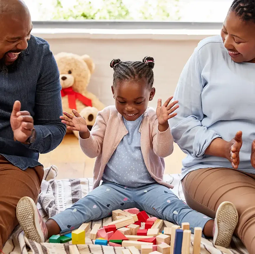 Parents sitting with little girl encouraging her through ABA therapy, behavioral skills a development - Collinsville, IL